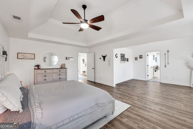 bedroom with a raised ceiling, ceiling fan, and dark wood-type flooring