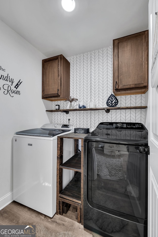 laundry room featuring hardwood / wood-style flooring, cabinets, and separate washer and dryer