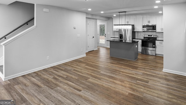 kitchen featuring dark wood-type flooring, decorative light fixtures, a kitchen island, white cabinetry, and stainless steel appliances