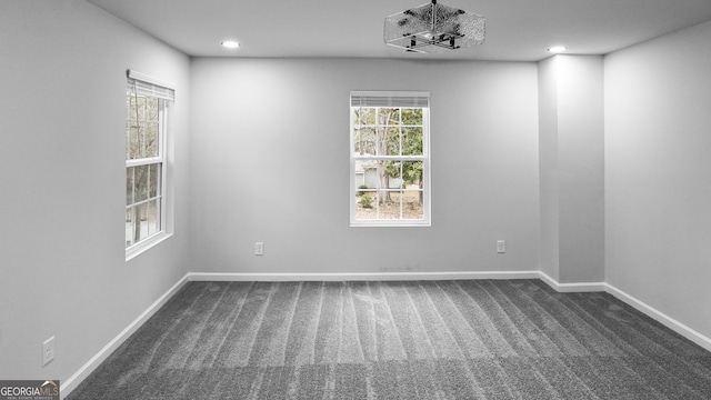 carpeted spare room with a notable chandelier