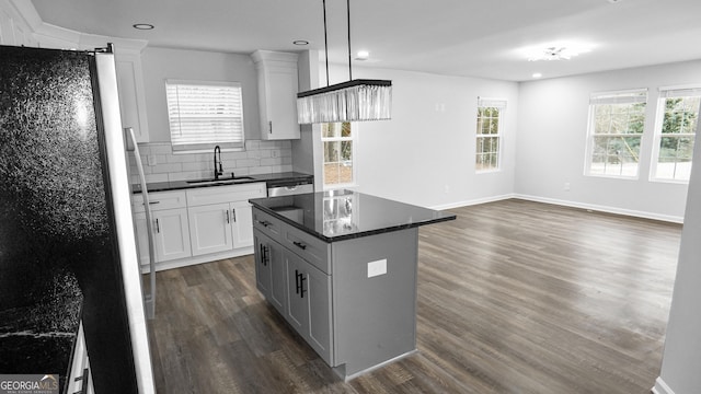 kitchen featuring white cabinetry, sink, pendant lighting, fridge, and a kitchen island