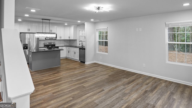 kitchen with stainless steel appliances, a healthy amount of sunlight, dark wood-type flooring, sink, and white cabinets