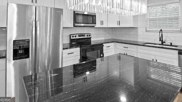 kitchen with dark stone counters, sink, white cabinets, and stainless steel appliances