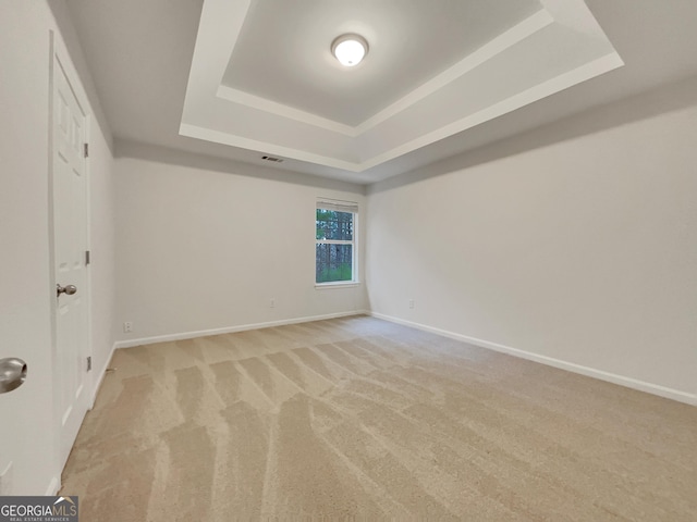 unfurnished bedroom featuring a tray ceiling and light colored carpet