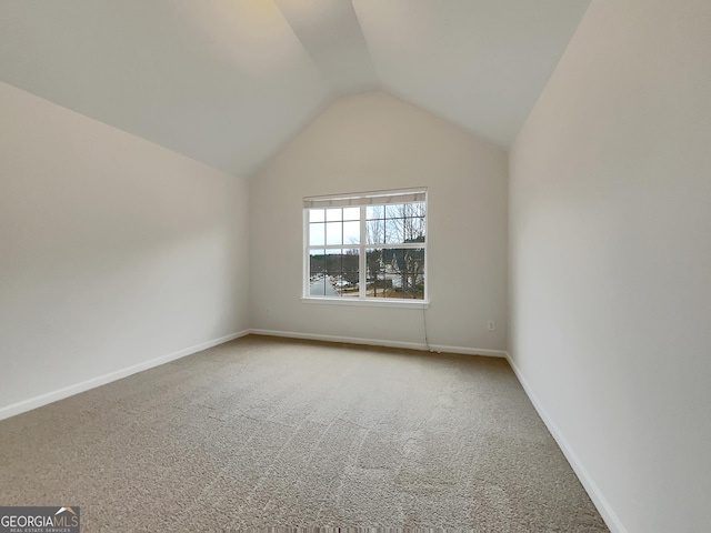 carpeted spare room featuring vaulted ceiling