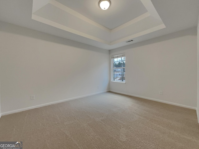 carpeted empty room featuring a raised ceiling