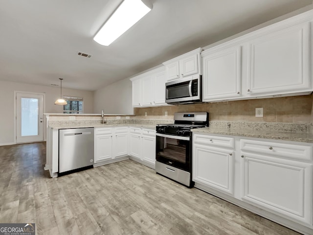 kitchen with backsplash, light hardwood / wood-style floors, pendant lighting, white cabinets, and appliances with stainless steel finishes