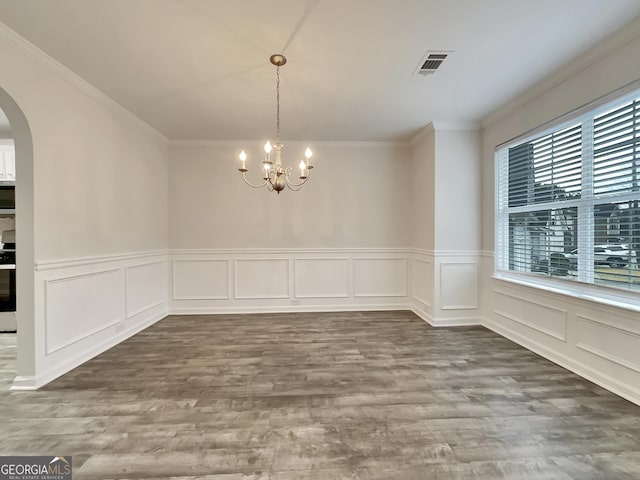 unfurnished dining area with hardwood / wood-style floors, an inviting chandelier, and crown molding