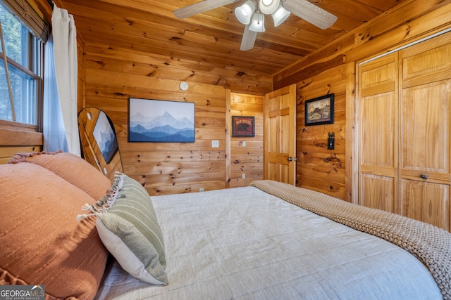 bedroom with ceiling fan, wood walls, wooden ceiling, and a closet