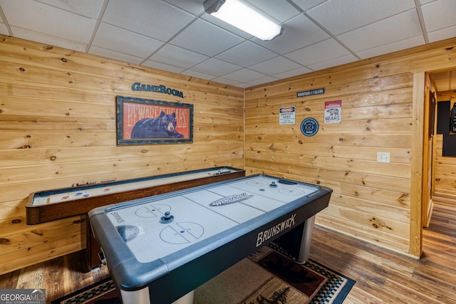 playroom featuring wooden walls, a drop ceiling, and dark hardwood / wood-style floors