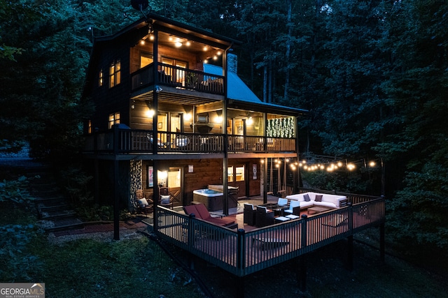 back house at twilight featuring a balcony, an outdoor hangout area, and a patio