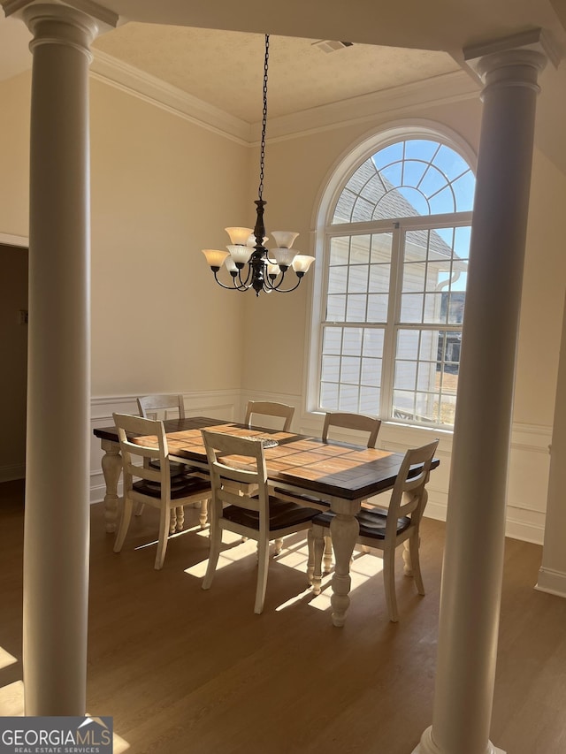 dining area featuring wood-type flooring, an inviting chandelier, a wealth of natural light, and crown molding