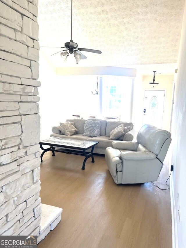 living room with light hardwood / wood-style floors, a stone fireplace, and vaulted ceiling