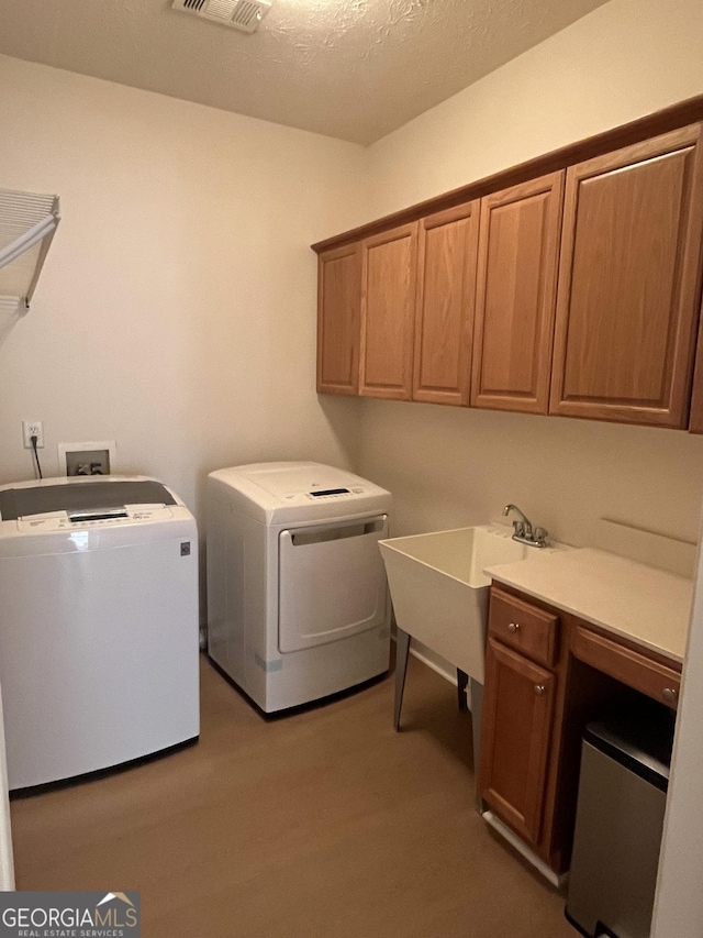 laundry area featuring washer and dryer, cabinets, light wood-type flooring, and sink