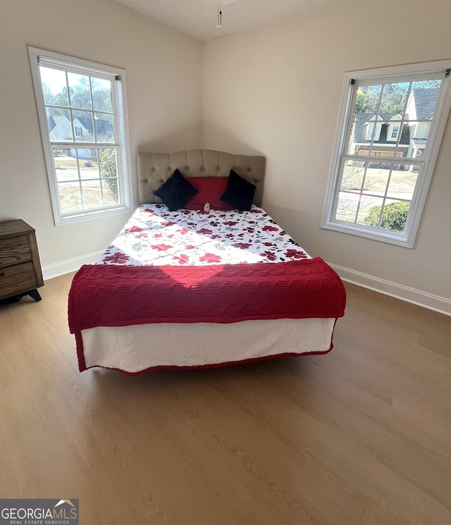 bedroom with multiple windows and hardwood / wood-style floors