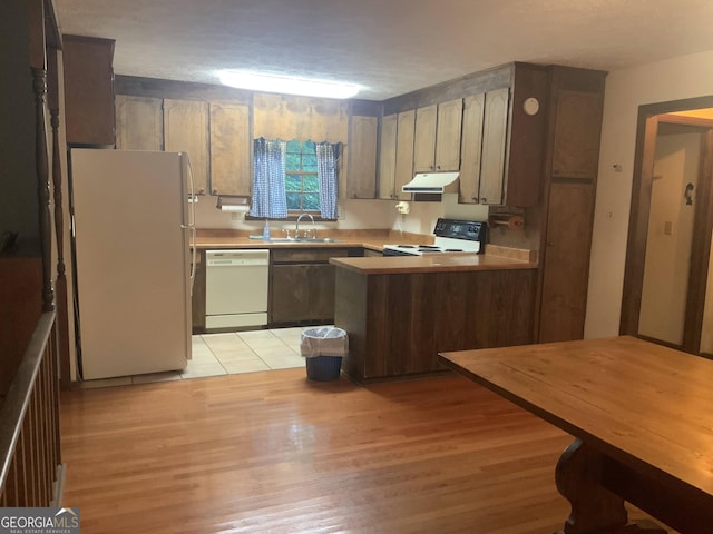 kitchen with kitchen peninsula, white appliances, sink, and light hardwood / wood-style flooring