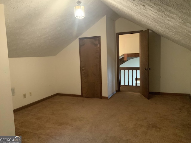 additional living space featuring vaulted ceiling, carpet floors, and a textured ceiling