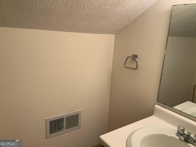 bathroom with a textured ceiling and sink