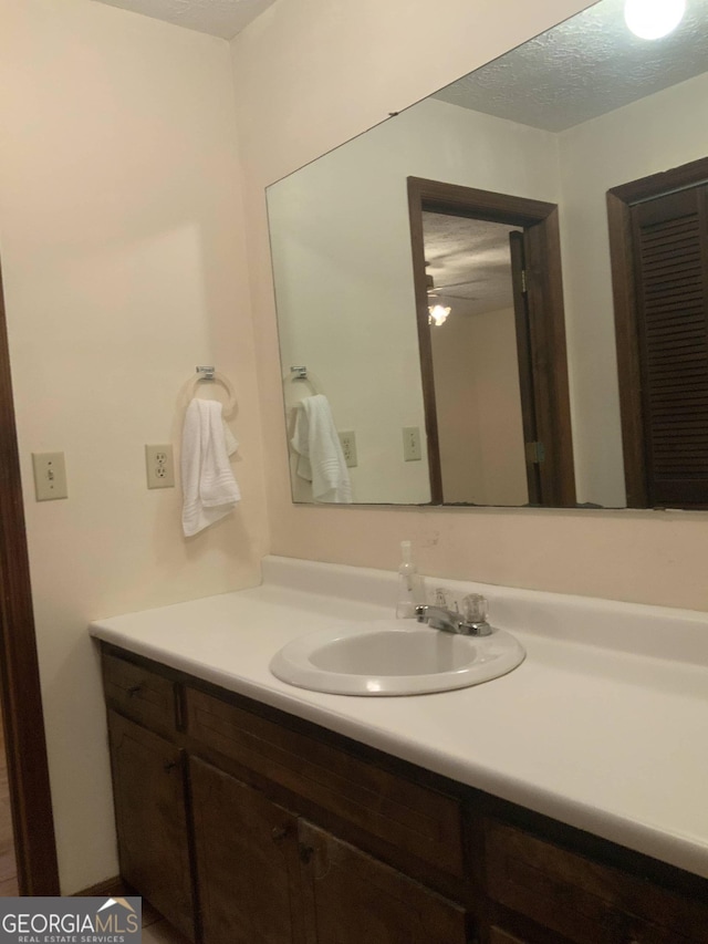 bathroom featuring ceiling fan, vanity, and a textured ceiling