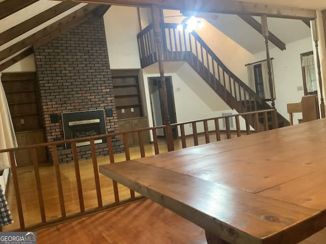 dining area featuring a fireplace, lofted ceiling with beams, and hardwood / wood-style flooring