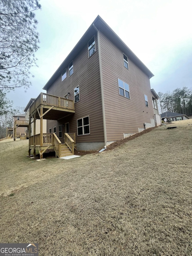 rear view of house with a lawn and a wooden deck