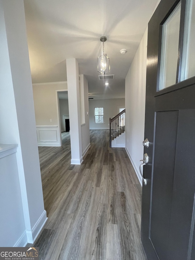 entrance foyer featuring visible vents, wainscoting, stairway, dark wood-type flooring, and a decorative wall