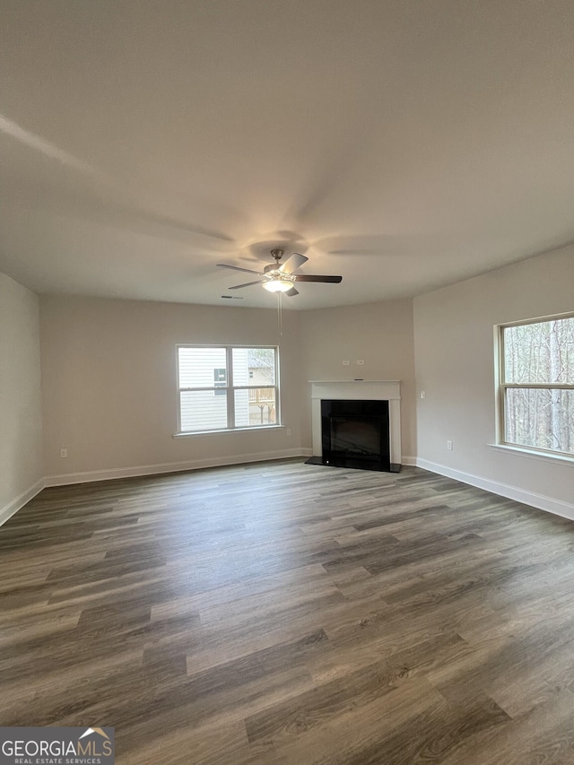 unfurnished living room featuring ceiling fan and dark hardwood / wood-style flooring