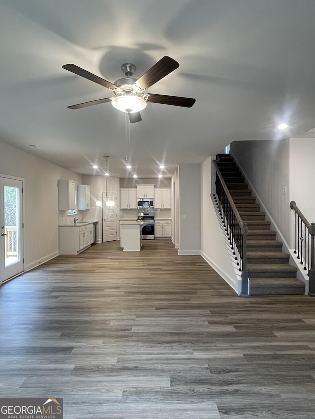 unfurnished living room featuring wood-type flooring, ceiling fan, and sink