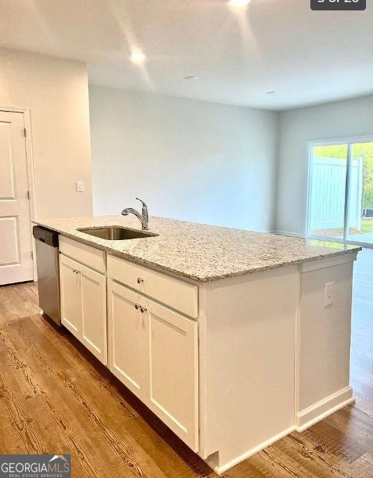 kitchen featuring dishwasher, light stone countertops, white cabinets, and a kitchen island with sink