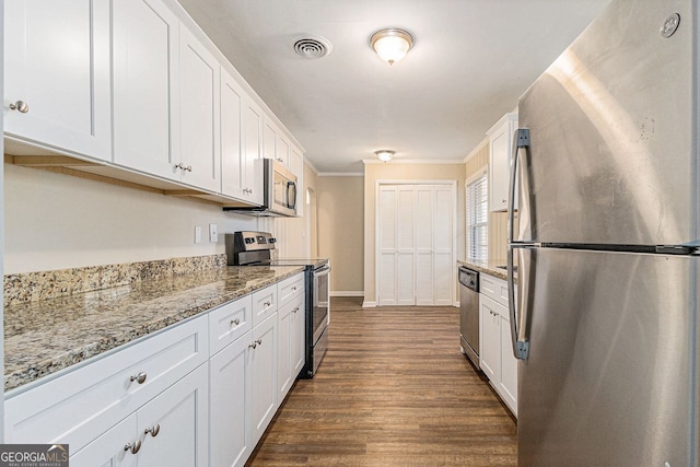 kitchen featuring dark hardwood / wood-style floors, light stone countertops, ornamental molding, appliances with stainless steel finishes, and white cabinetry