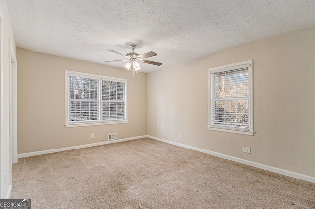 carpeted spare room with a textured ceiling and ceiling fan