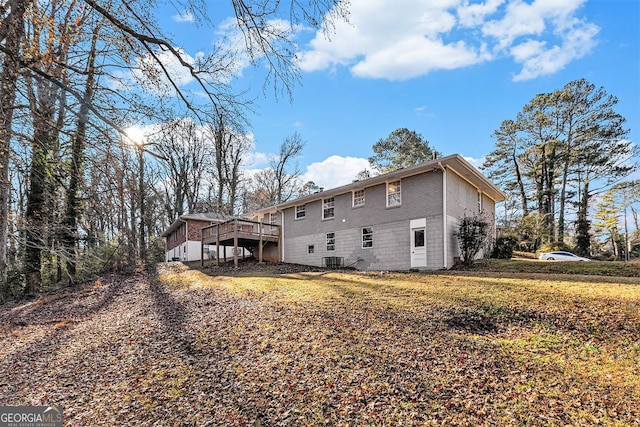 back of property with a lawn, a deck, and central AC