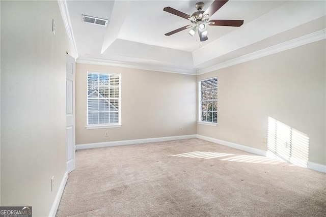 spare room featuring light carpet, a tray ceiling, ceiling fan, and ornamental molding