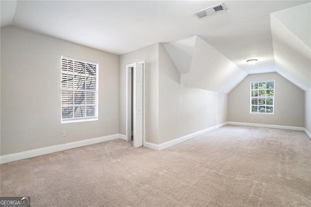 additional living space with light carpet and vaulted ceiling