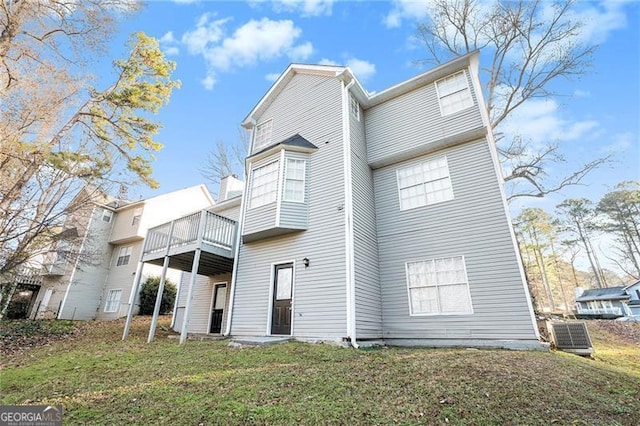 rear view of property featuring a lawn and a deck