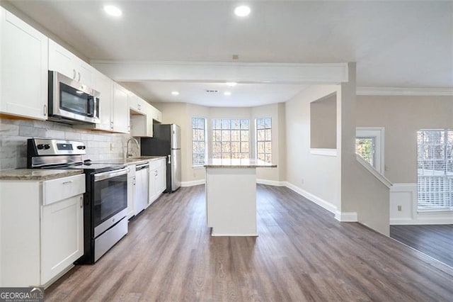 kitchen featuring decorative backsplash, appliances with stainless steel finishes, dark wood-type flooring, crown molding, and white cabinetry