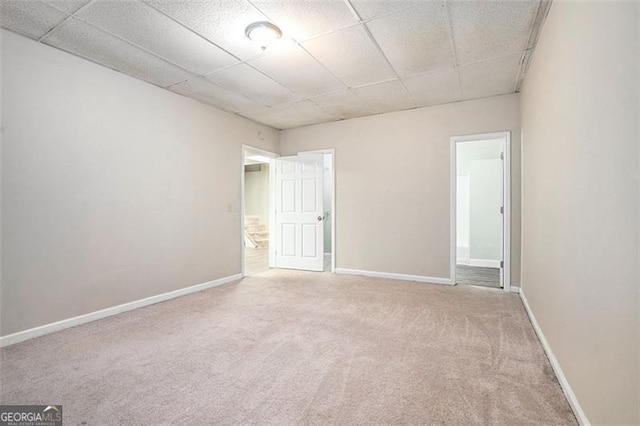 empty room featuring carpet and a paneled ceiling