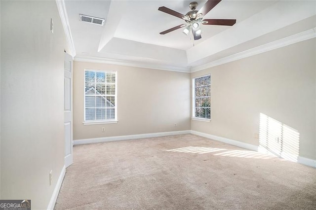 carpeted empty room featuring a raised ceiling, ceiling fan, and crown molding