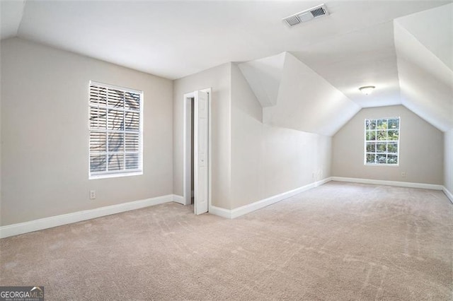 bonus room with light colored carpet and lofted ceiling