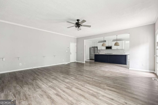 unfurnished living room with ceiling fan, wood-type flooring, and crown molding