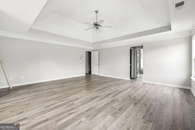 unfurnished living room with light wood-type flooring, a tray ceiling, and ceiling fan