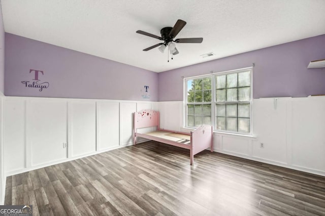 unfurnished bedroom featuring ceiling fan, hardwood / wood-style floors, and a textured ceiling