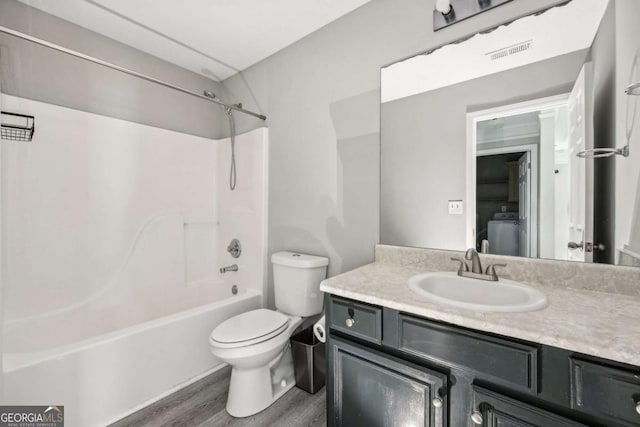 full bathroom with hardwood / wood-style floors, vanity, bathing tub / shower combination, toilet, and washer / clothes dryer