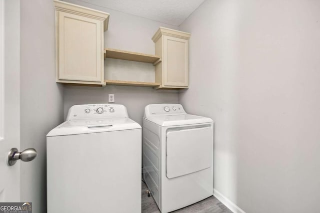 laundry area featuring cabinets, light hardwood / wood-style flooring, washer and dryer, and a textured ceiling