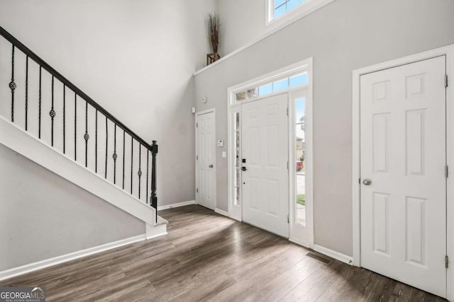 entryway with a towering ceiling, dark hardwood / wood-style floors, and a wealth of natural light