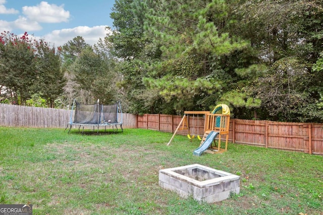 view of yard with a playground, a trampoline, and an outdoor fire pit