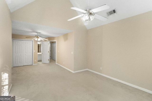 unfurnished bedroom with ceiling fan, a closet, light carpet, and vaulted ceiling