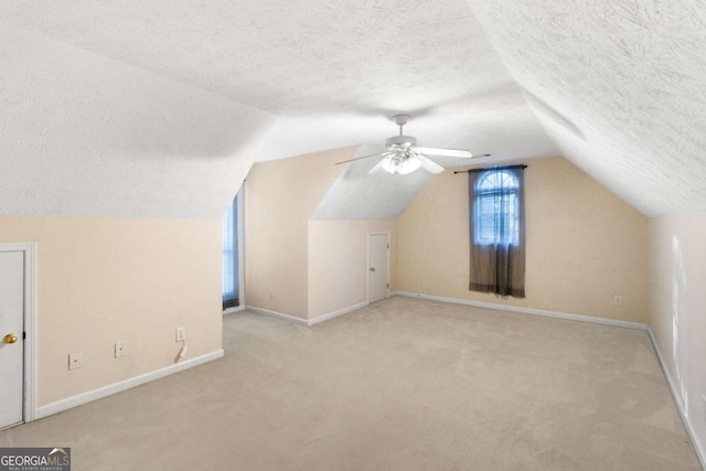 additional living space with a textured ceiling, ceiling fan, light carpet, and vaulted ceiling