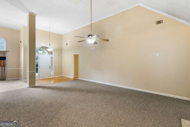 carpeted empty room with a textured ceiling, high vaulted ceiling, ceiling fan, and crown molding