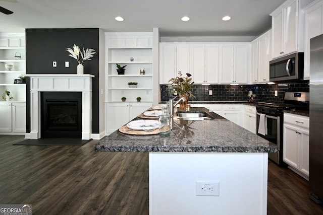 kitchen with white cabinets, appliances with stainless steel finishes, sink, and an island with sink